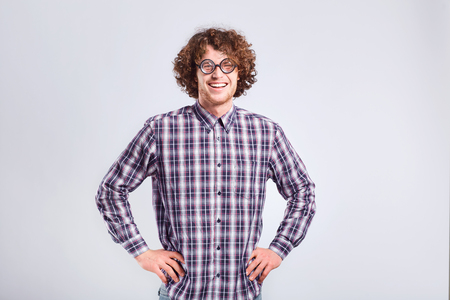 Curly nerd man in glasses with a stupid kind of funny emotion on a gray background.の写真素材