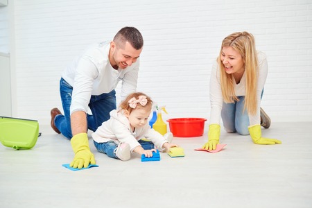 A happy family is washing the floor against a white wall.の写真素材