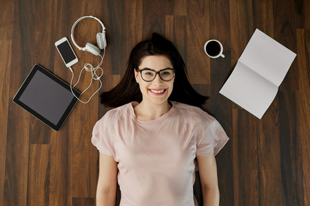 Top view of a positive student girl with glasses smiles lies on the floor.の写真素材