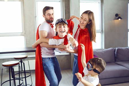 Happy family in superhero costumes playing together in a room.の写真素材