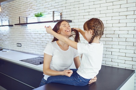 Happy mother and daughter are smiling in the kitchen in the house. Mothers Day.の写真素材