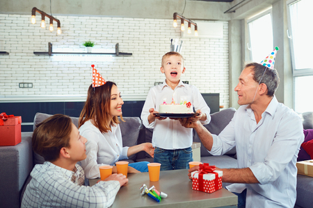 A family with a candle cake celebrates a birthday party in a room.の写真素材
