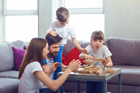 Happy family playing board games at home. Mother, father and children play together.の写真素材
