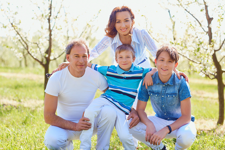 Happy family sitting on nature in spring, summer.Mother, father and sons in the field.