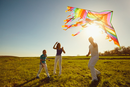 Happy family playing with a kite on nature in spring, summer.Mother, father and sons in the field.の写真素材