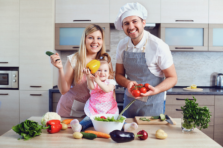 A happy family prepares food from vegetables in the kitchen.の写真素材