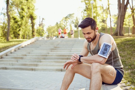 A male runner looks at a smart watch on his arm.の写真素材