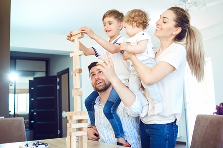 A cheerful family plays board games sitting at a table indoors.の写真素材