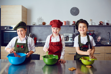 A group of children preparing a dough at the table in the kitchen.の写真素材