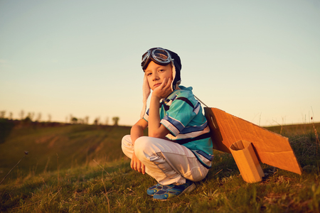A happy boy  is playing with an airplane on the nature at sunset.の写真素材