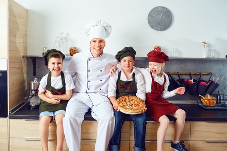 Funny children learn to cook in the classroom in the kitchen.の写真素材