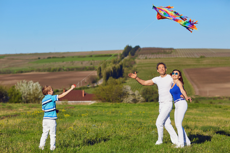 Happy family with a kite playing in the field in nature.の写真素材