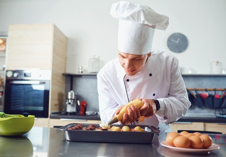 A confectioner in uniform prepares cupcakes in the kitchen.の写真素材