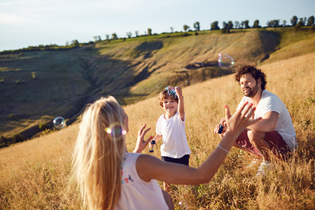 The family is playing with soap bubbles in nature.の写真素材