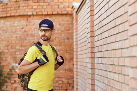 A man in sportswear with a backpack against a brick wall background.の写真素材