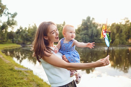 Mother and baby playing on grass in summer park.の写真素材