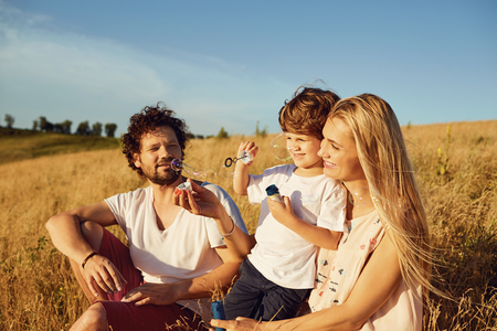 The family is playing with soap bubbles in nature.の写真素材