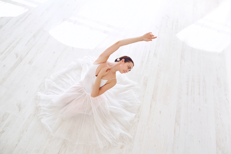 A ballerina in white clothes in a white light studio.の写真素材