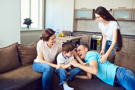 The family plays together fun on the couch indoors.の写真素材