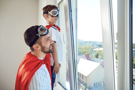 Father and son at the window in the room. Fathers Day.の写真素材