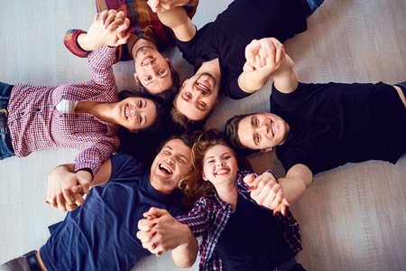 Top view. A group of friends are laughing lying on the floor in room.