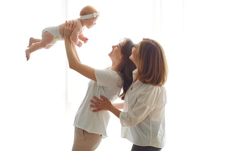 Mother, grandmother and toddler on hands on a white background. A family.