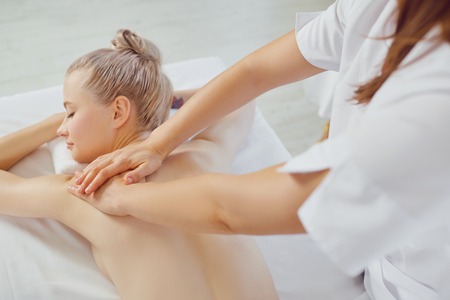 Body massage. Beautiful blond woman in spa salon doing body massage.の写真素材