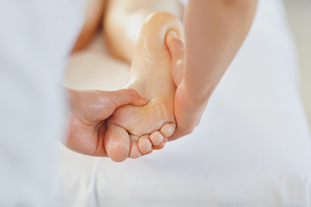 Foot massage in the massage room. Masseur makes foot massage to a woman.の写真素材