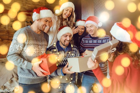 Cheerful friends with gifts celebrating Christmas. A group of young people in a room with a...
