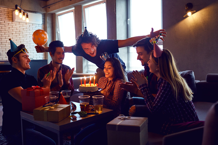 Friends with birthday cake  celebrating birthday at a party in room.の写真素材