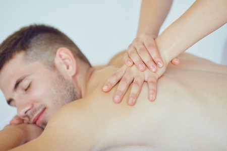 Back massage for a man lying on the table in the spa salon.の写真素材