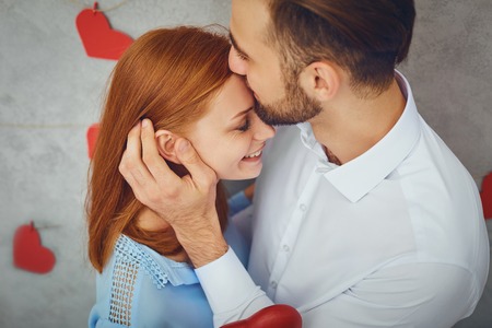 Valentines Day. A loving couple with hearts in their hands are smiling on a gray background with hearts.の写真素材