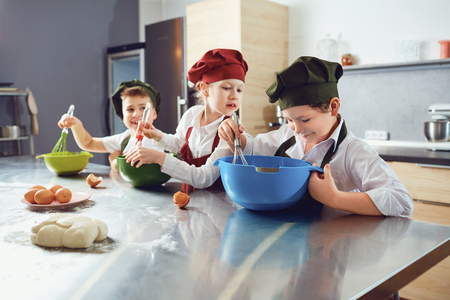 A group of children are cooking at the table in the kitchen.の写真素材
