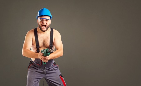 Funny builder with a drill in his hands on a background for text.