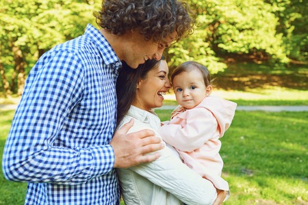 Happy family standing playing in the park. Mother, father and daughter are walking in the park in...