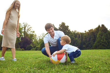 Family with a child playing with a ball in the park in the summer.の写真素材