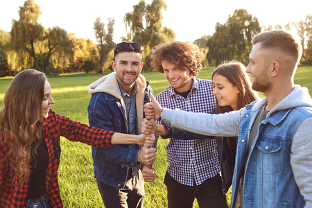 Group of friends connected thumb up in the park in summer spring, autumn.