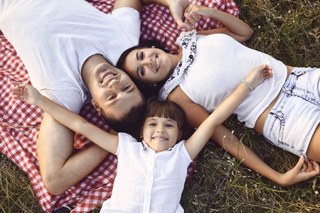 Funny family smiling lying on grass in nature in summer autumn.