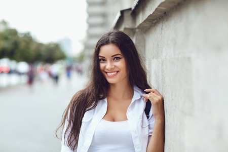 Beautiful happy brunette woman smiling outdoors on city street. Portrait of a girl.の写真素材