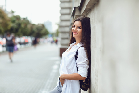 Beautiful happy brunette woman smiling outdoors on city street. Portrait of a girl.の写真素材