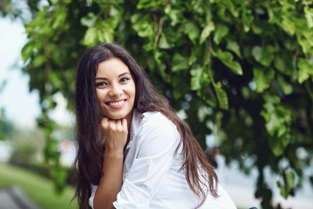 Beautiful happy brunette woman smiling outdoors on city street. Portrait of a girl.の写真素材