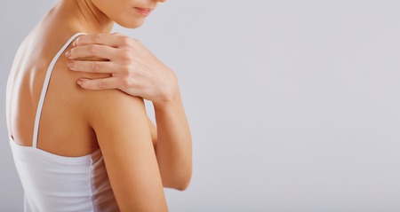 Pain, injury in the shoulder. Woman holds her shoulder with her hand.の写真素材