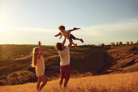 Happy family having fun playing at sunset in summer outdoors.の写真素材