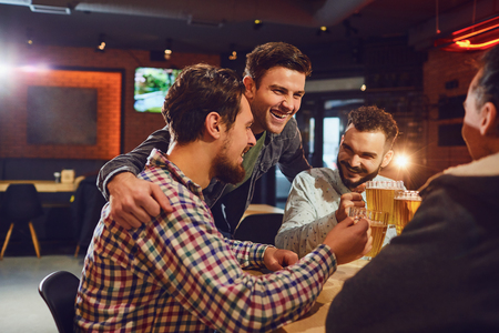 Friends talk, drink beer in a bar. Young people in a meeting in a pub.の写真素材