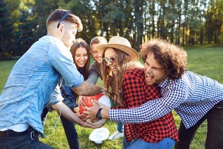 Cheerful friends playing with a ball in the park in the summer spring autumn .の写真素材