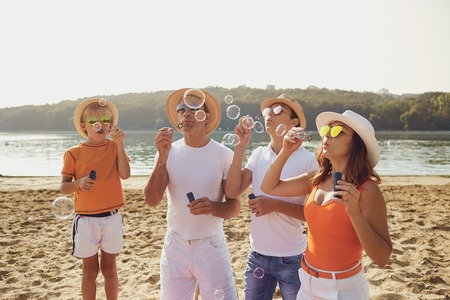 Family with soap bubbles playing on the beach in summer park.の写真素材