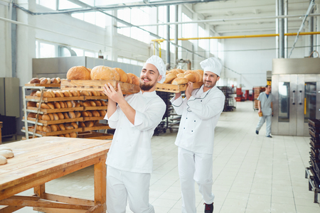 Bakers are holding a tray of bread at a bread factory bakery.の写真素材