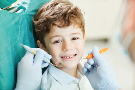 Beautiful child smiling while sitting in the dentists chair. Close-up.の写真素材