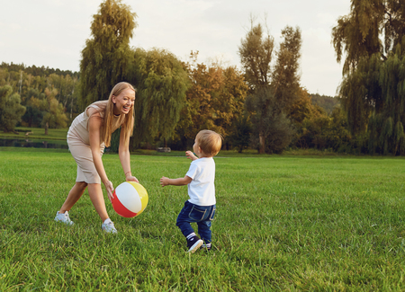 Mother with a child plays in the park on the grass.の写真素材