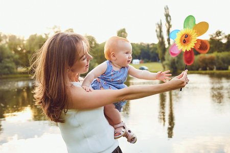 Mother and baby playing on grass in summer park.の写真素材